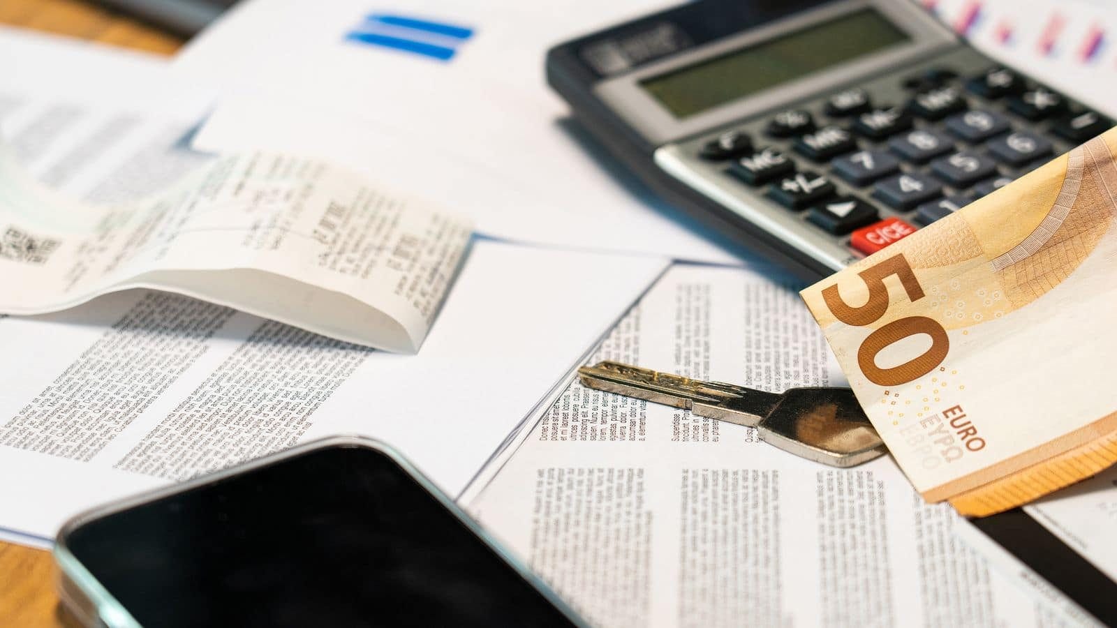 Calculadora, billete de cincuenta euros y presupuestos impresos sobre una mesa de oficina